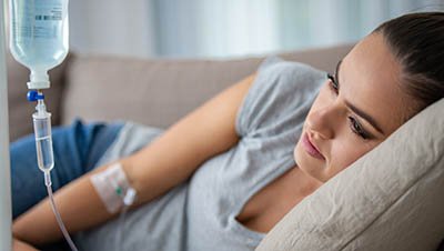 Девушка лежит под капельницей на диване